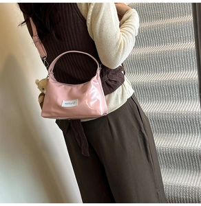 Detail of pink glossy patent leather shoulder bag with a cute bear plush keychain