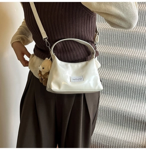 Glossy white crossbody bag with cute teddy bear charm and adjustable shoulder strap