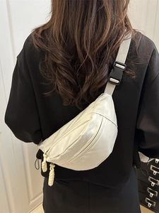 White nylon crossbody chest bag with adjustable strap worn by a model in a modern room