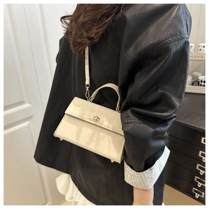Detail of a creamy white PU leather handbag with gold twist lock and metal feet