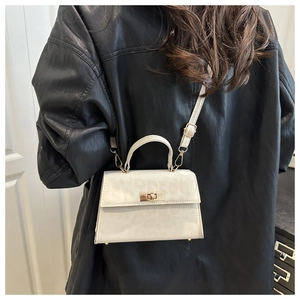 Detail of cream leopard embossed crossbody bag with gold hardware on black jacket