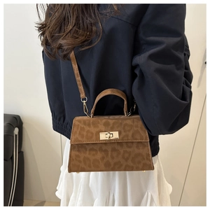 Fashionable leopard print handbag with golden twist lock worn by a model in a blue coat
