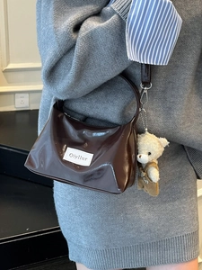 Dark brown patent leather shoulder bag with plush bear charm and brand label