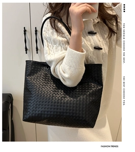 Close-up of a large black woven leather tote bag shown on model for daily commuting