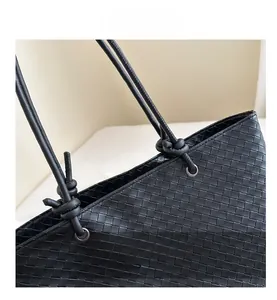 Detail view of black woven faux leather tote with knotted rope strap and metal eyelets