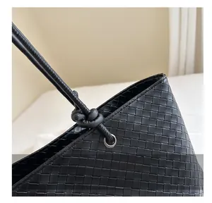Macro detail of black woven tote bag featuring leather texture and knotted strap design