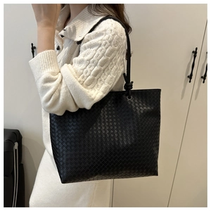Close-up of black woven leather tote bag texture and shoulder strap on model