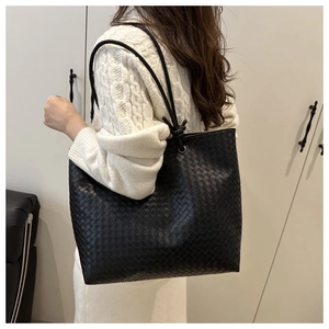 Close-up of black woven leather tote bag with elegant intrecciato texture and slim straps
