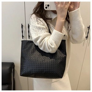 Detail of a large black woven leather tote bag shown in a casual mirror selfie style