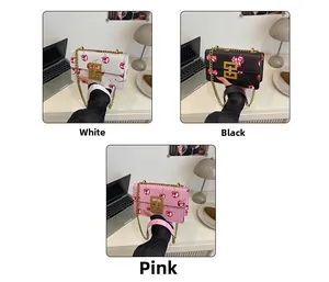 Close-up of cherry print crossbody bags in white, black, and pink with gold chain straps