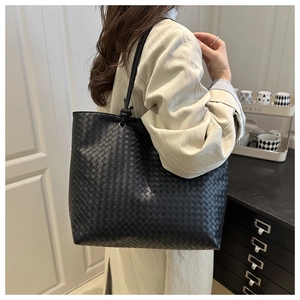 Close-up of black leather woven texture and knot handle on large tote bag