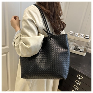 Detail view of large black woven leather tote bag featuring elegant knotted strap design