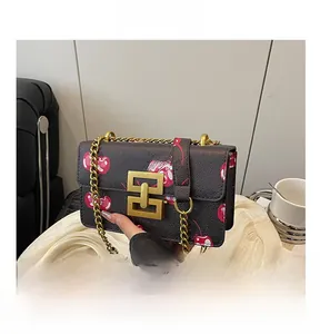 Detail of crossbody bag with cherry print, litchi texture and gold interlocking lock