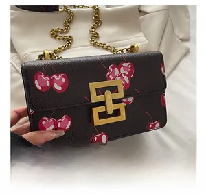 Detail showing the dark fabric cherry print texture and golden geometric metal lock buckle