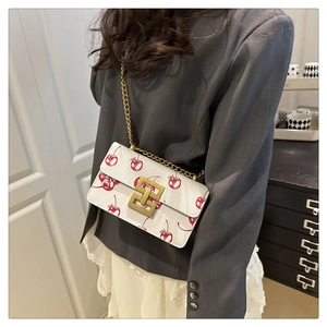Detail of white leather shoulder bag with cherry print and golden geometric clasp