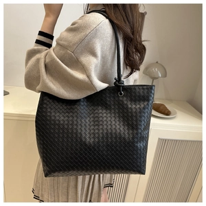 Detailed view of the luxury black woven leather texture on a spacious tote bag