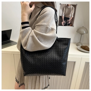 Detailed view of the woven leather texture and metal buckle on the black tote bag