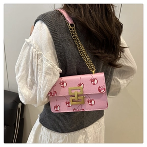Detail of pink cherry print crossbody bag with gold H-buckle and elegant chain strap