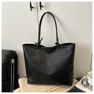 Detail of black woven tote bag featuring leather braiding and silver ring hardware