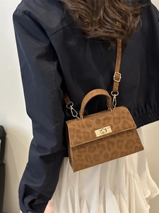 Chic leopard print handbag with gold clasp shown on model wearing white skirt