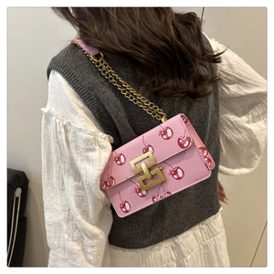 Close-up of pink cherry print crossbody bag with gold chain and metal buckle on shoulder