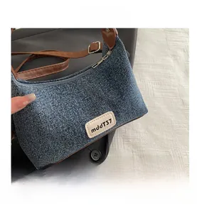 Close-up of denim hobo bag featuring brown leather strap and silver zipper detail