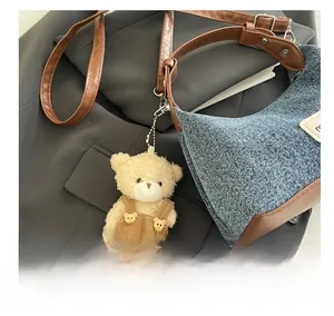 Detail of vintage denim patchwork shoulder bag with a plush bear charm accessory