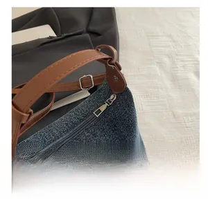 Detail of smooth metal zipper and brown leather strap on retro blue denim bag