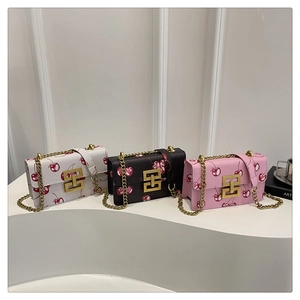 Detailed view of cherry print crossbody bags in three colors with gold chain straps