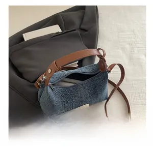 Detail of blue denim hobo bag with brown leather straps and beige woven label