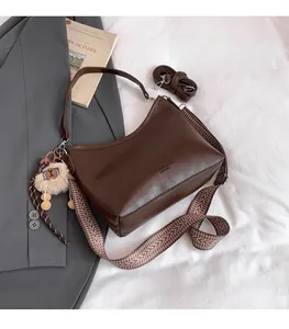 Détail du sac hobo marron foncé avec bandoulière géométrique et pendentif en peluche