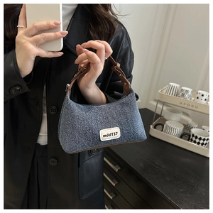 Detail of blue denim hobo bag showing its vintage texture and brown leather strap handle