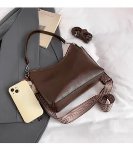 Comparaison de taille du sac à bandoulière marron foncé avec smartphone et sangle