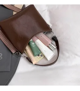 Détail de l'intérieur d'un sac à bandoulière marron foncé montrant un grand espace de rangement