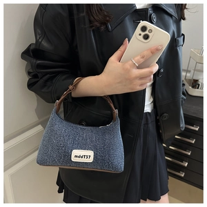 Denim underarm bag with leather strap shown in a real-life styling lifestyle shot