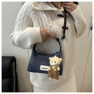 Detail of blue tweed dumpling bag with adjustable strap and cute teddy bear charm