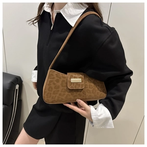 Détail d'un sac baguette imprimé léopard avec boucle dorée porté à l'épaule