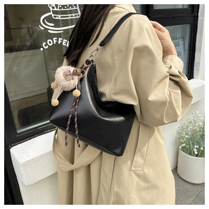 Détail du sac cabas en similicuir noir avec pompon et décoration en corde tressée