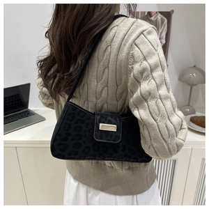 Détail d'un sac porté épaule imprimé animal noir avec fermoir doré sur un pull en maille beige
