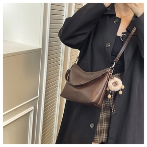 Détail d'un sac bandoulière en cuir PU marron avec charme en peluche et bandoulière réglable