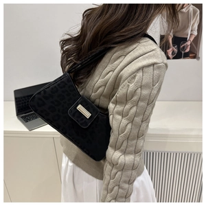Détail du sac bandoulière vintage léopard noir avec boucle dorée sur le mannequin