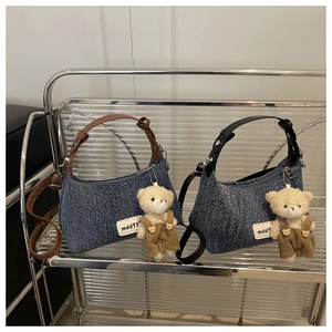 Detail of denim shoulder bags with mddT logo and cute bear plush charm on side