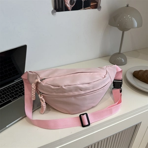 Minimalist pink canvas waist bag for women with adjustable strap on a desk background
