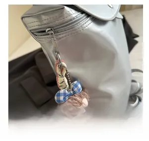 Dettaglio del ciondolo a forma di orsetto di peluche con fiocco blu su uno zaino argento