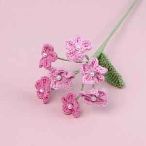 Handmade pink crochet forget-me-not flowers with pearl centers on a solid background