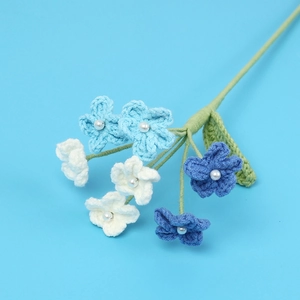Hand-crocheted blue and white flower bouquet with pearl centers on a blue background