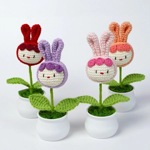 Détail de quatre plantes en pot de lapin crochetées à la main en rouge, violet et rose