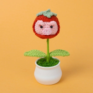 Close-up of handmade crochet pink pig plant in a white pot with green leaves