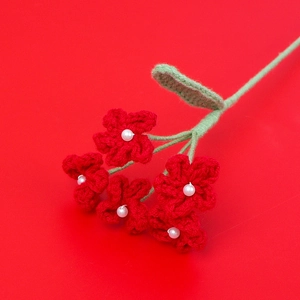 Detailed view of handmade red crochet flowers with white pearl center and green stems