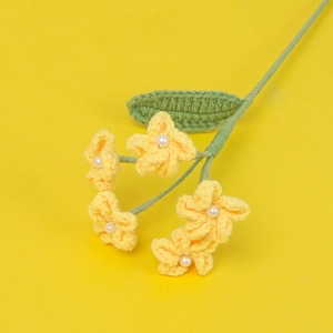 Close-up of handmade crochet forget-me-not flowers in yellow with pearl bead centers